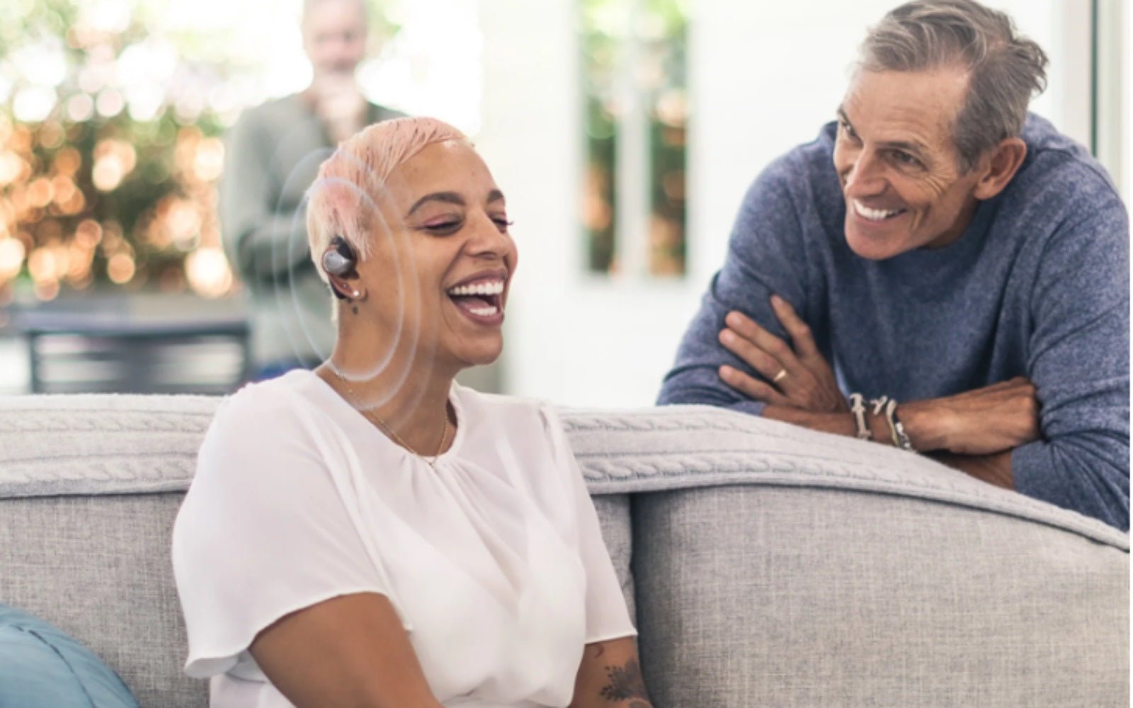 Person wearing a hearing aid while talking with family nearby